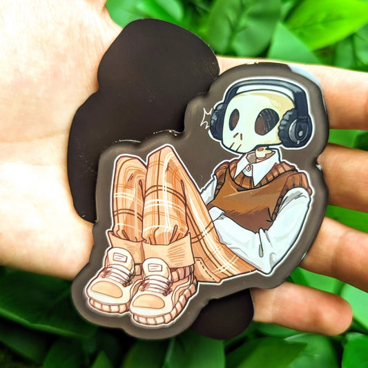 Front and back of a magnet with an aesthetic skeleton reclined and relaxed while listening to his favorite tunes.