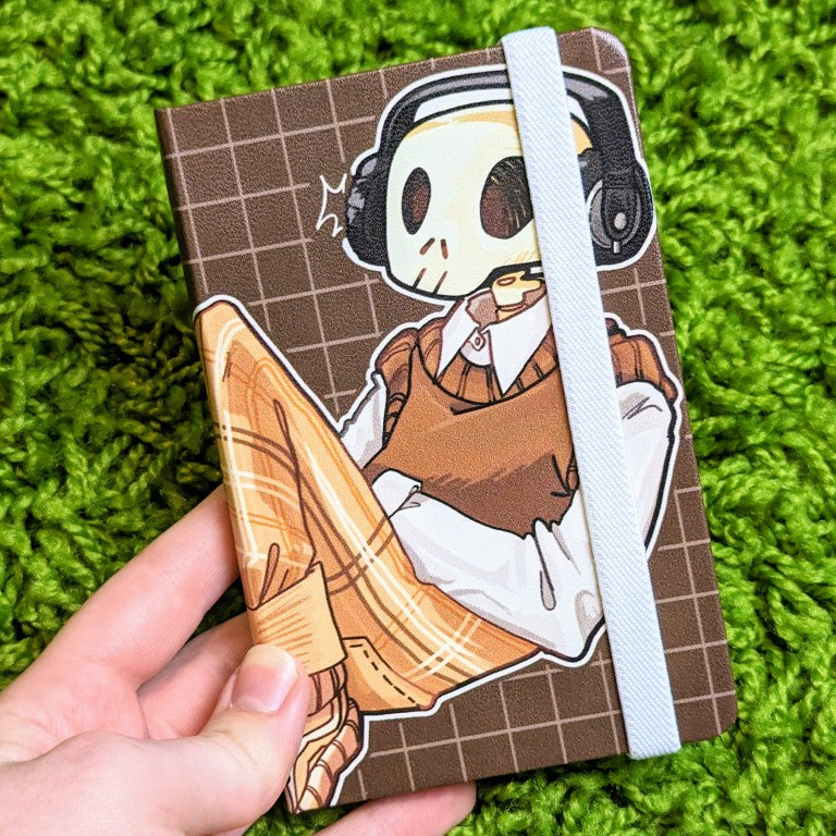Front cover of a sketchbook with an aesthetic skeleton design and the elastic band wrapped over it