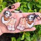 Two aesthetic skeleton keychains showing Cade reclined and relaxed while listening to his favorite tunes.
