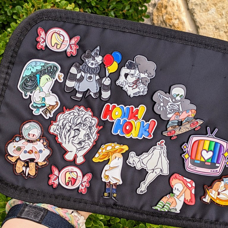 A collection of enamel pins by Milky Tomato on display